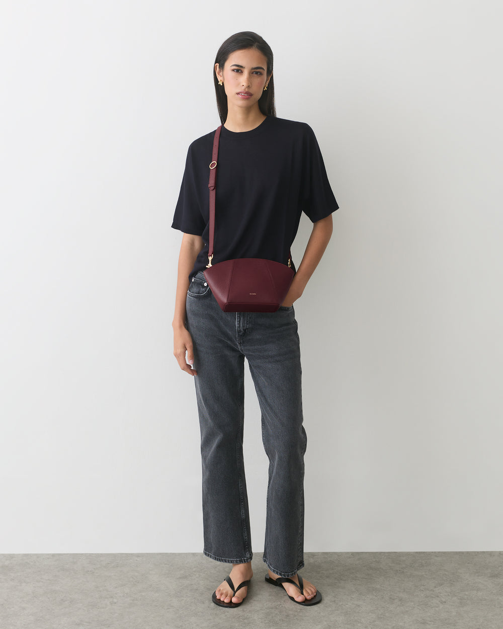 Person in t-shirt and jeans with a belt bag over shoulder.