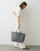 Person holding large handbag, wearing a sweater draped over shoulders.