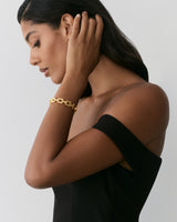 Person wearing an off-shoulder dress and bracelet, touching their hair.