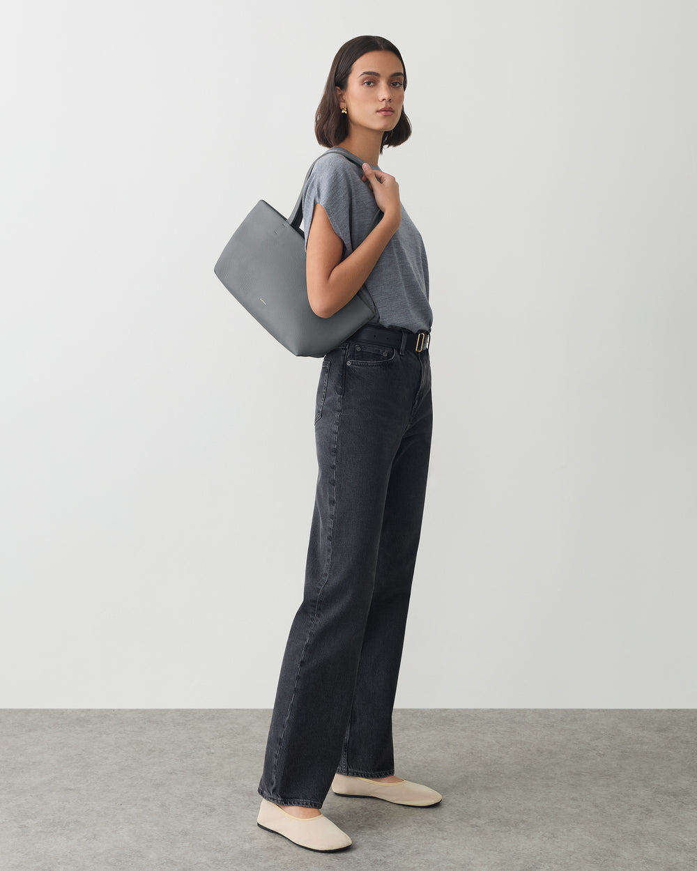 Person in casual outfit holding a tote bag over shoulder.