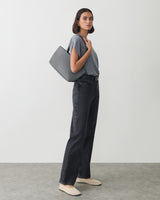 Person in casual outfit holding a tote bag over shoulder.