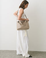 Woman in a sleeveless top and long skirt carrying a shoulder bag.