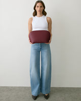 Person holding a large curved clutch, wearing sleeveless top and wide-leg jeans.