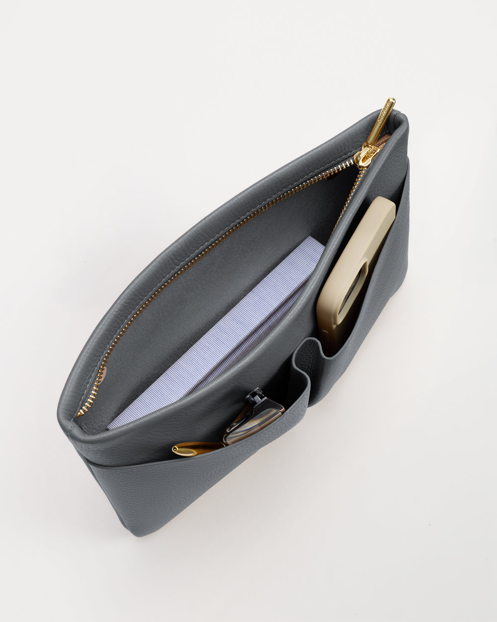 Open handbag with a book and a phone inside on a white background.