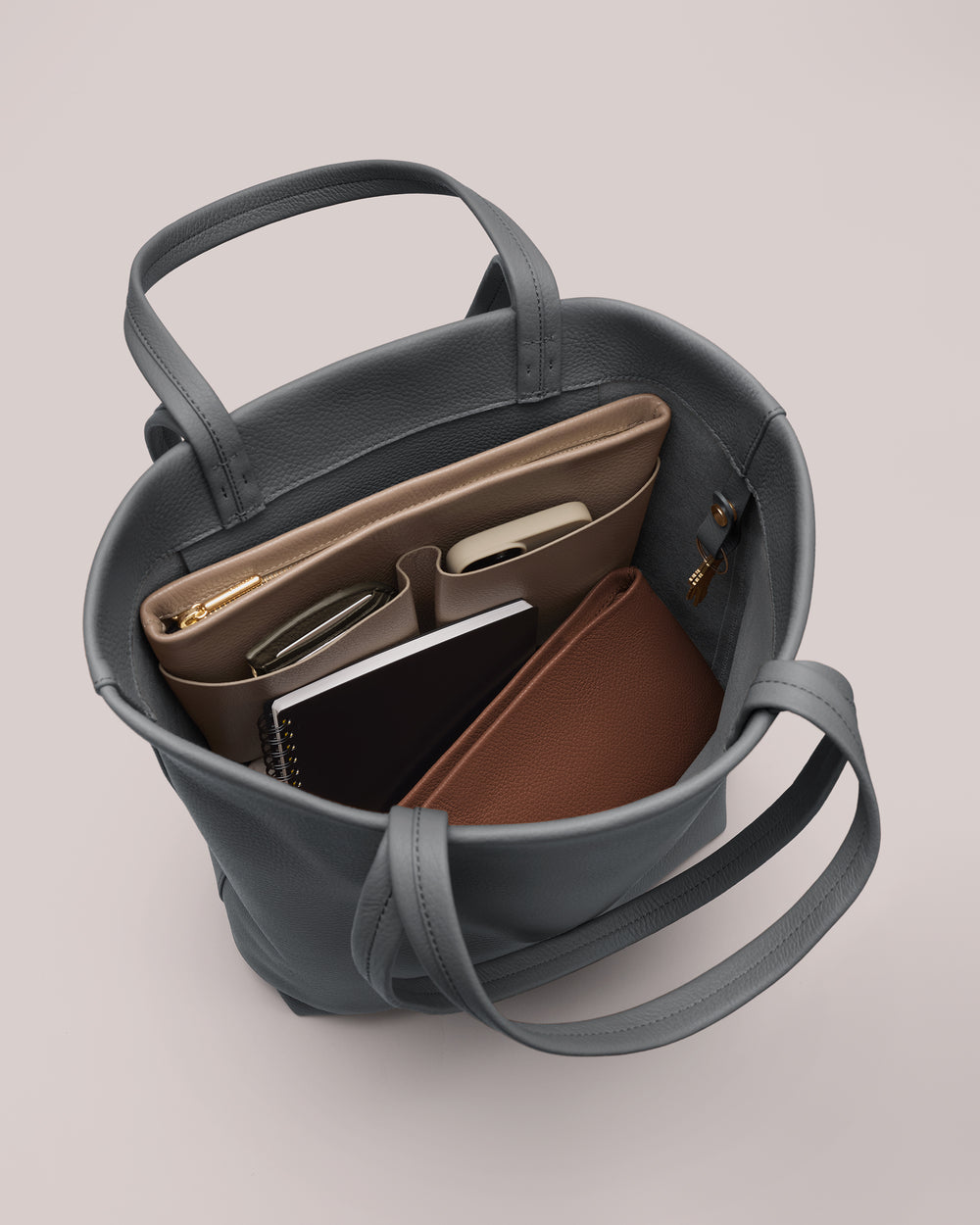 Open bag with items like books, wallet, phone, and pen inside.