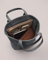 Open bag with items like books, wallet, phone, and pen inside.