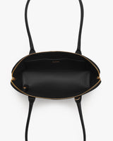 Open top view of a handbag with long straps and an interior pocket