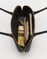 Open handbag with contents including keys, phone, pouch, and tube.