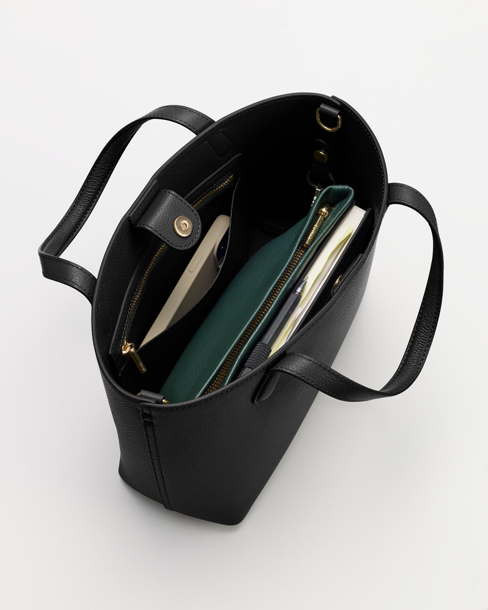 Open tote bag with pockets containing books and a green pouch.