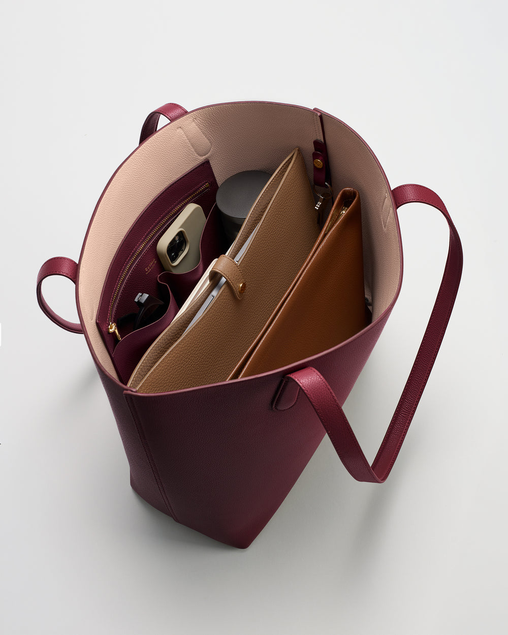 Open tote bag with various items inside, including a notebook and a small pouch.