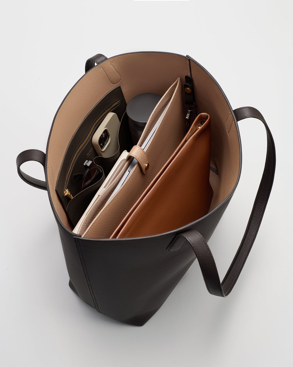 Open tote bag filled with a water bottle, tablets, and a pair of glasses.