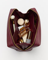 Open toiletry bag with cosmetics and skincare items inside.