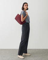 Person standing with a shoulder bag, wearing a t-shirt and jeans.
