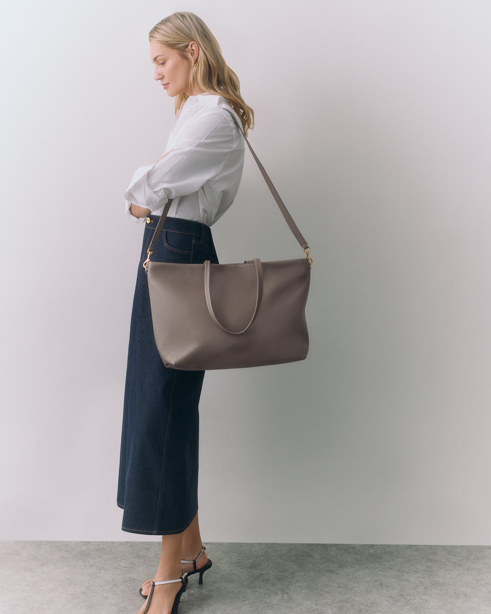 Person standing with shoulder bag wearing long skirt and sandals