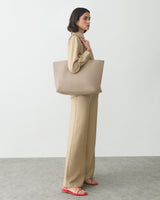 Person standing with tote bag wearing matching outfit and sandals.