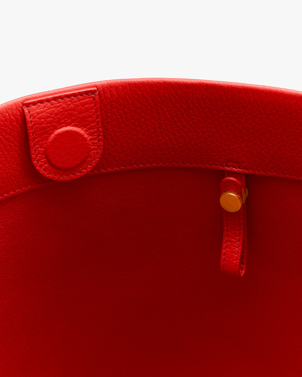 Open tote bag with a round button and a strap inside.