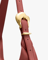 Close-up of a bag strap with a shiny metal buckle design.