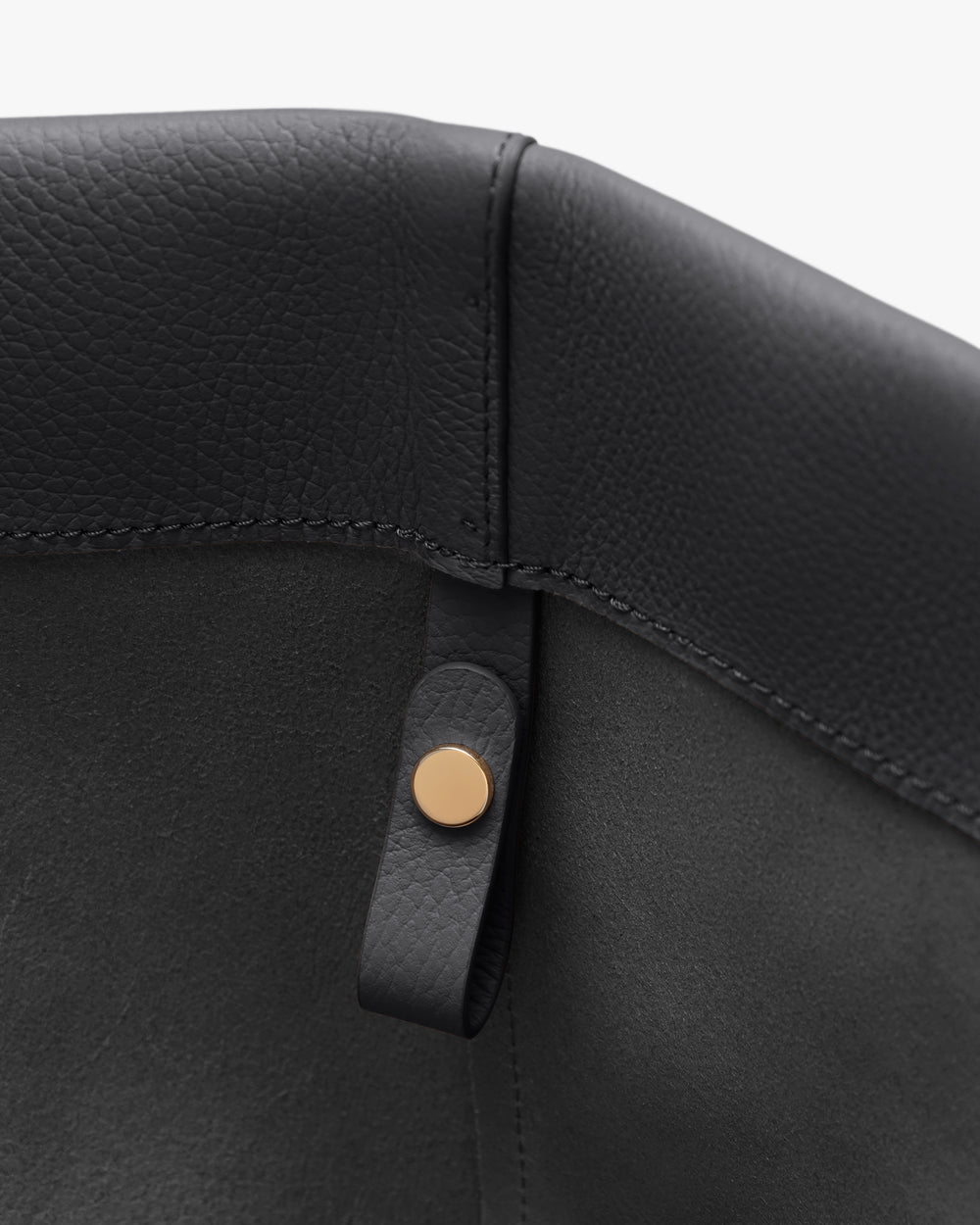 Close-up of a bag corner with a buttoned strap detail.