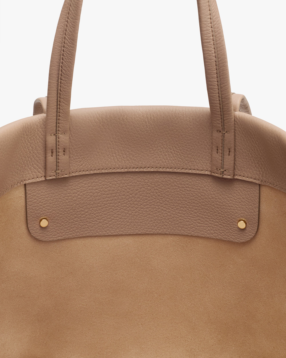 Close-up of a handbag's top handles and front detailing.