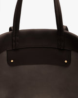 Close-up of a tote bag with two handles and metal studs.