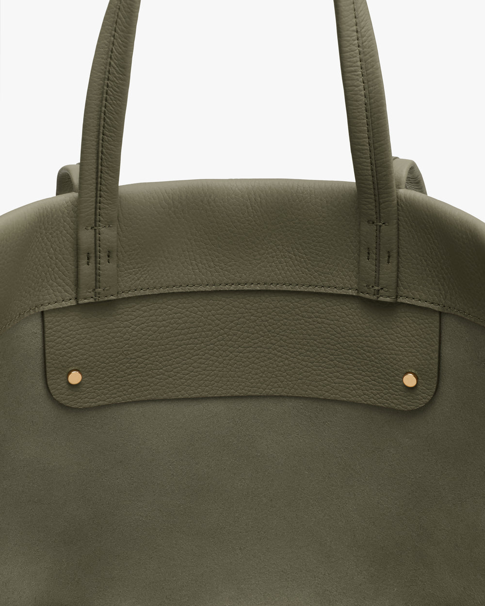 Close-up of a tote bag with short handles and gold studs on a flat surface.