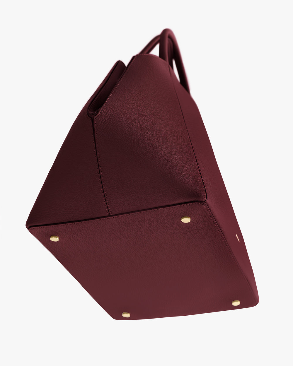 The image shows the bottom of a structured handbag with four metal feet.