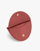 Round leather coin pouch with snap closure, open to show interior.