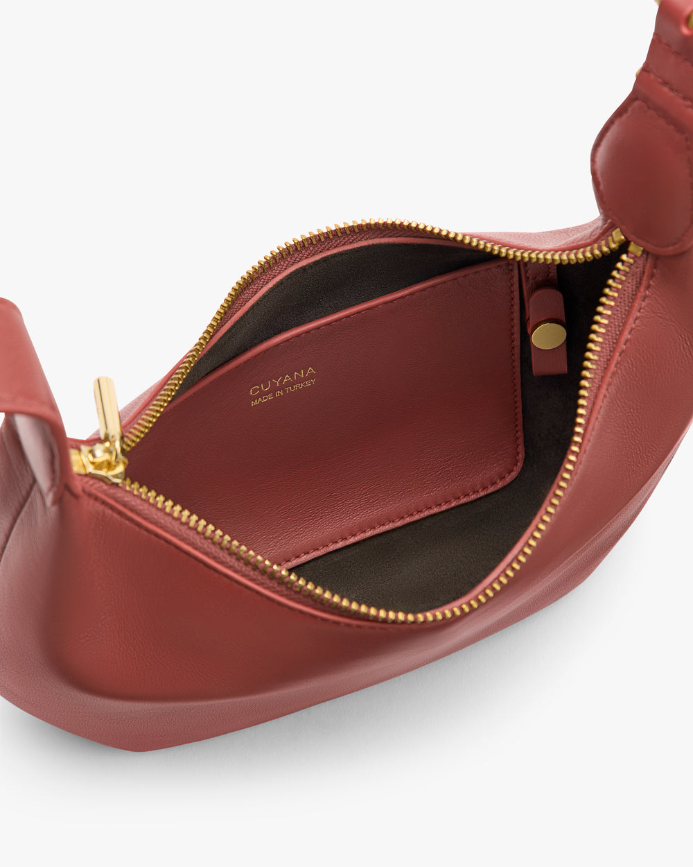Open handbag with zipper and inner pocket showing branding and small tube inside.