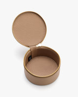 Round jewelry case with zipper, open lid, and textured surface.