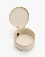 Round leather case with open lid and zipper, displaying simple interior design.