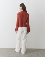 Person facing away wearing a long-sleeve top and wide-leg pants.