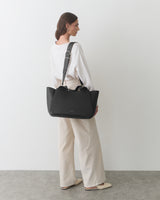 Person holding a large travel bag wearing a long-sleeve top and pants.