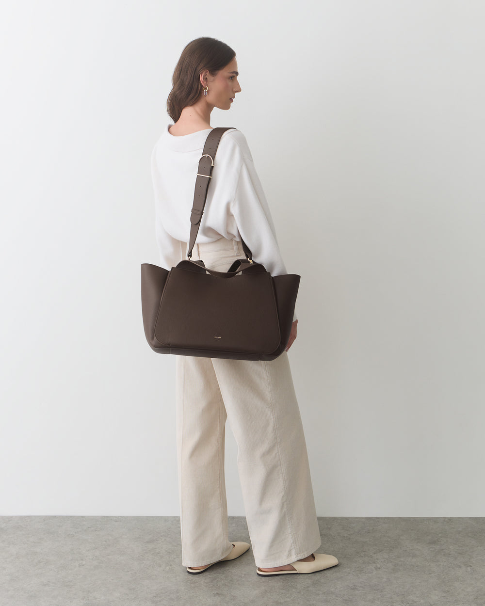 Person carrying a large travel bag over their shoulder.