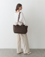 Person carrying a large travel bag over their shoulder.