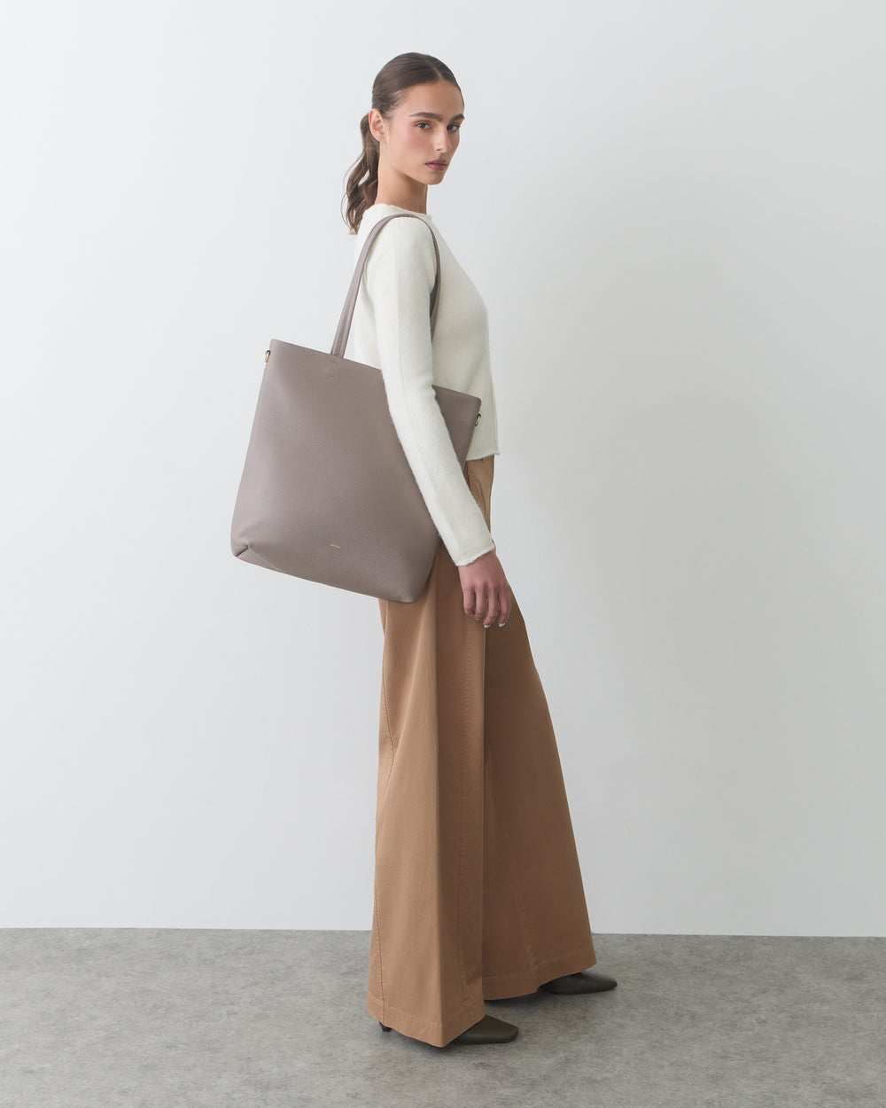 Person in long pants carrying a large shoulder bag.