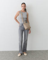 Person standing with a shoulder bag, wearing a sleeveless top and jeans.