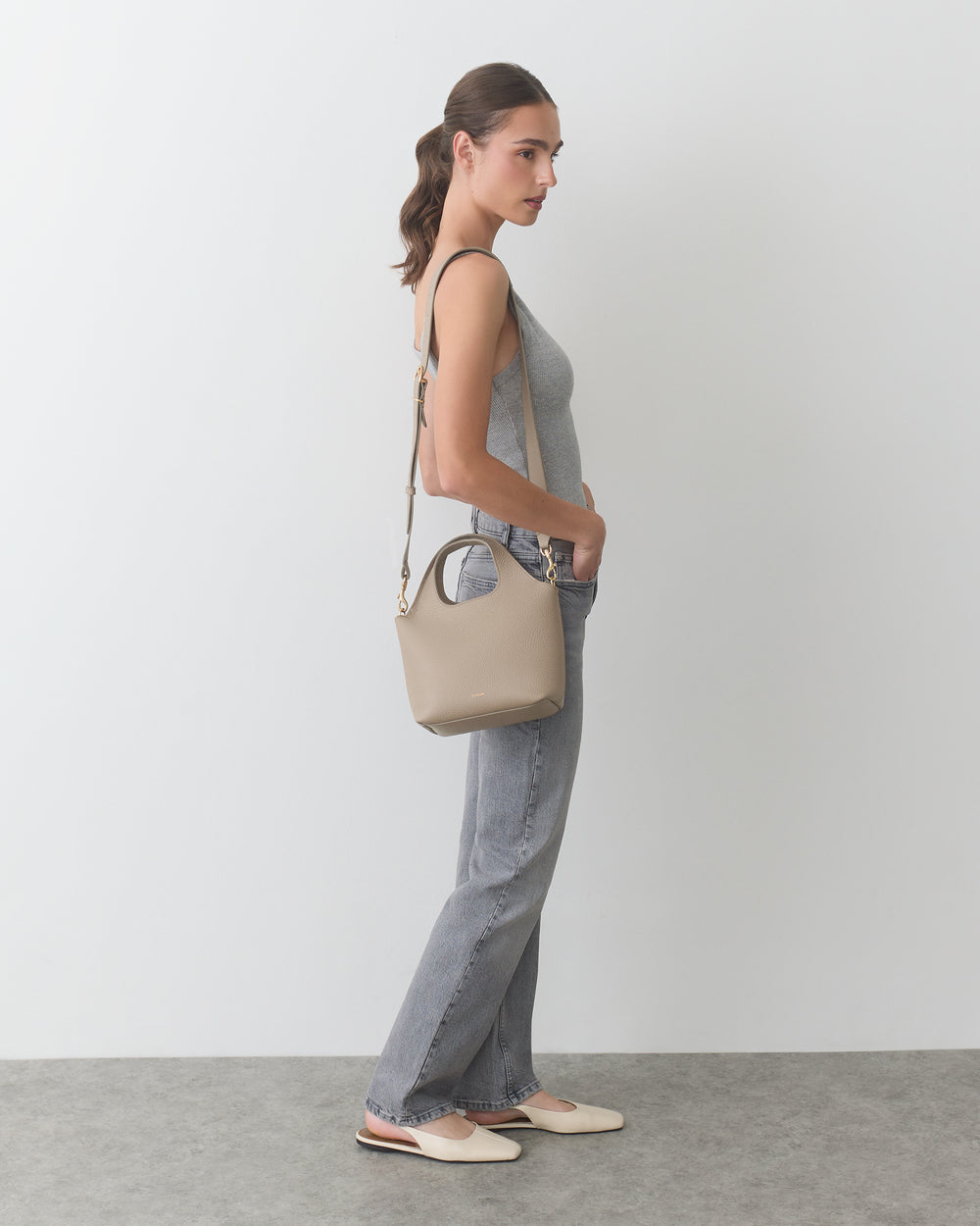 Person in sleeveless top and jeans carrying a shoulder bag.