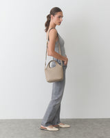 Person in sleeveless top and jeans carrying a shoulder bag.