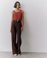 Woman in sleeveless top and wide-leg pants standing against a plain background.