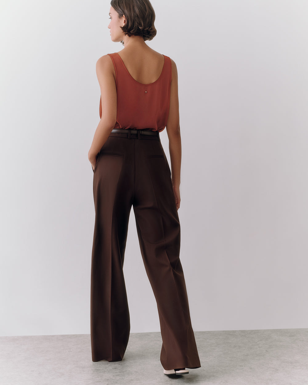 Person in sleeveless top and wide-leg pants standing on a plain background.