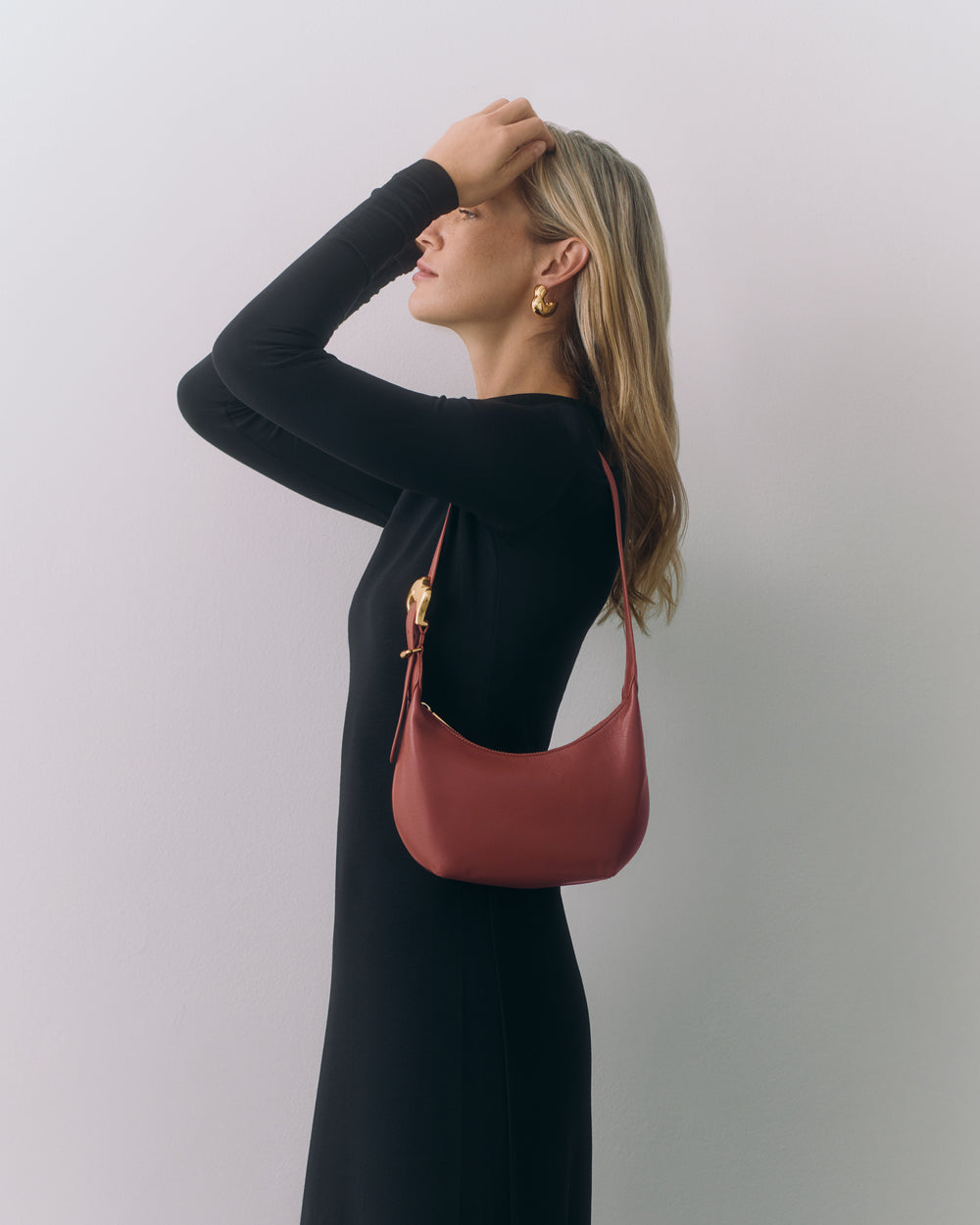 Person in dress holding small shoulder bag over shoulder.