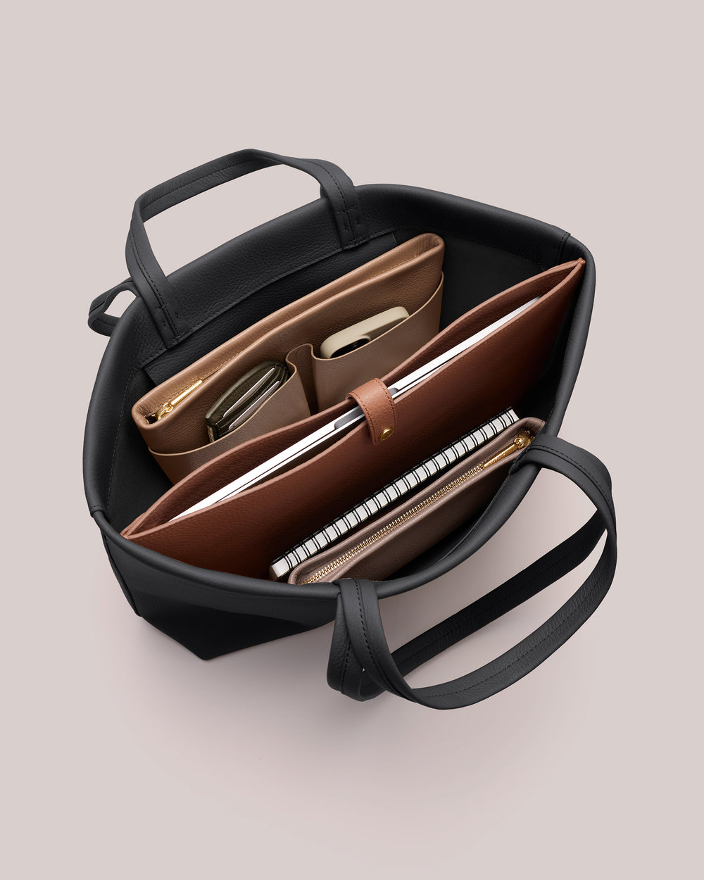 Open handbag with organized items including folders, notebook, and phone.