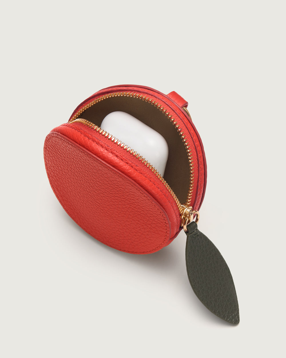 Round coin pouch open with a small white case inside.