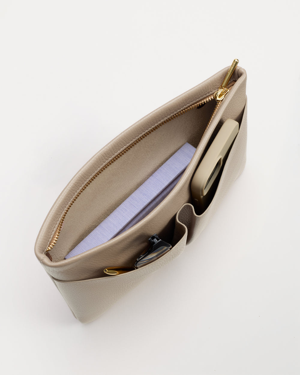 Open bag with a notebook, phone, and sunglasses inside.