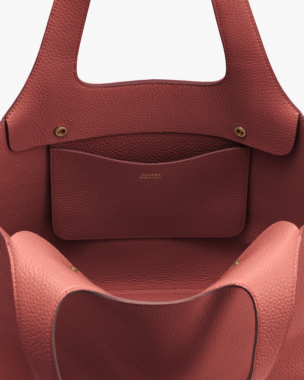 Open handbag with small internal pocket and gold button clasp details.