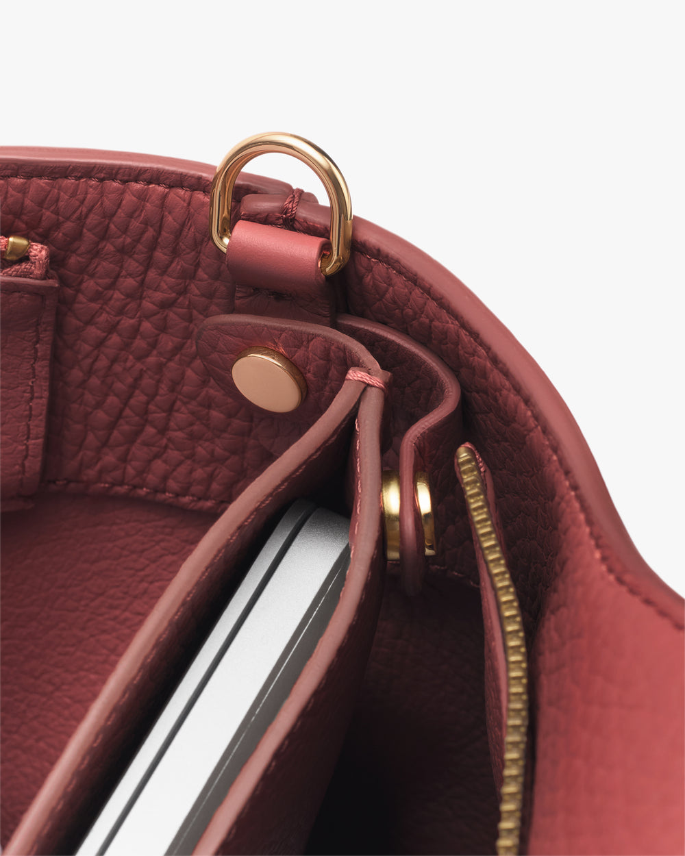 Open handbag with tablet inside, visible zipper and metal rings.