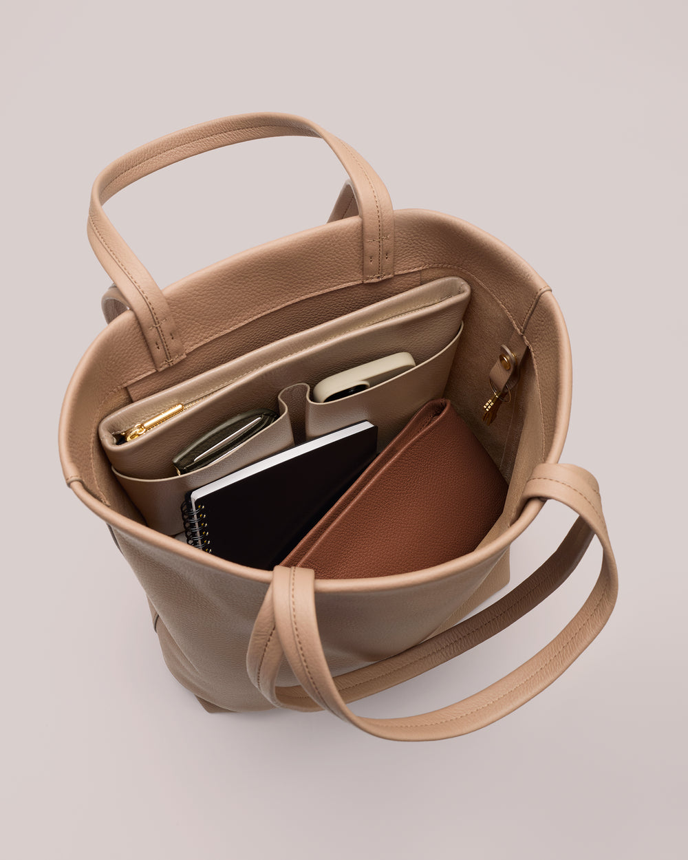 Open handbag with compartments holding notebook and items inside.