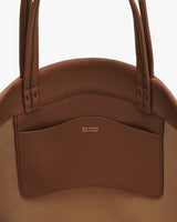 Round bag with two handles and a front pocket.