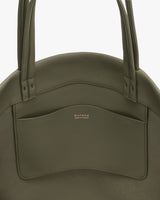 Round handbag with two long handles and a front pocket.
