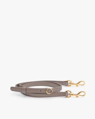 Leather strap with gold clasps laid flat.
